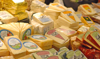 Many types of packaged cheeses in a deli case