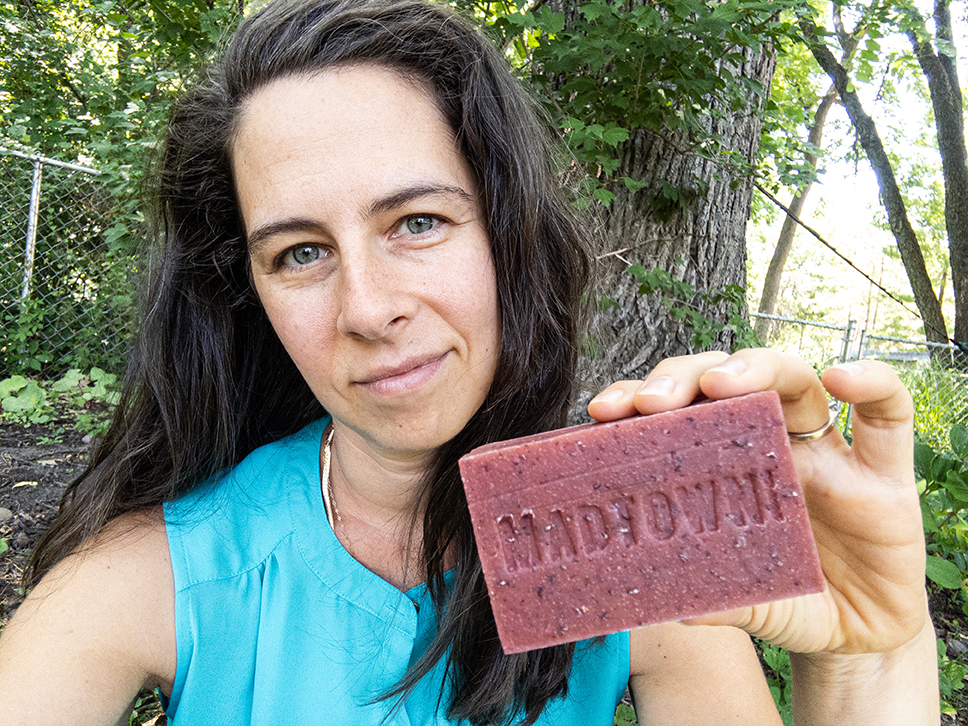 A woman holding a bar of soap that has "Madtown" embossed in it