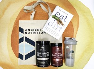 A tote bag, a book titled "Eat Dirt," a travel mug, and two bottles of protein powder