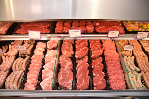 Many different cuts of meat in a butcher display case