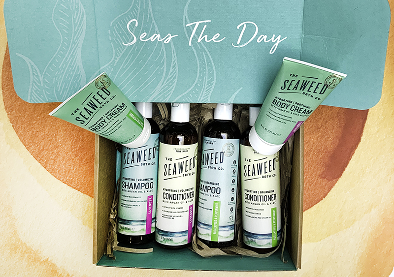 A gift box with body cream, shampoo, and conditioner - labelled "Seas the Day"