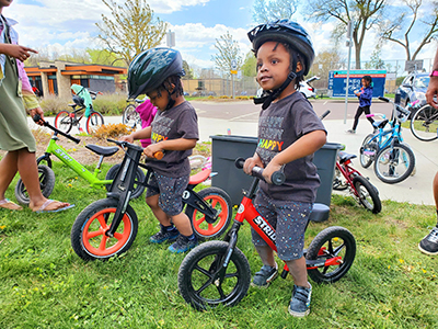 A group of very young children with helmets sitting on bikes