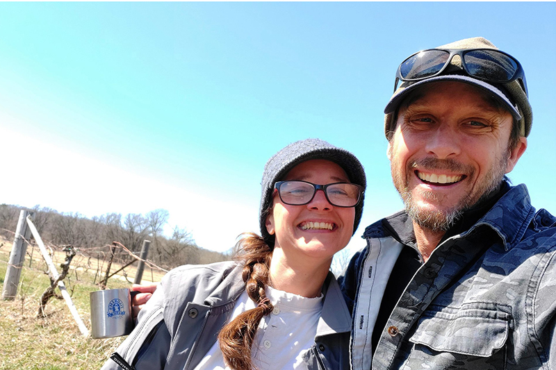 Cory Secher and Susan of Carandale Fruit Farm embracing in an orchard in early spring