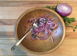 Overhead shot of slided red onions mixed with other ingredients before being picked