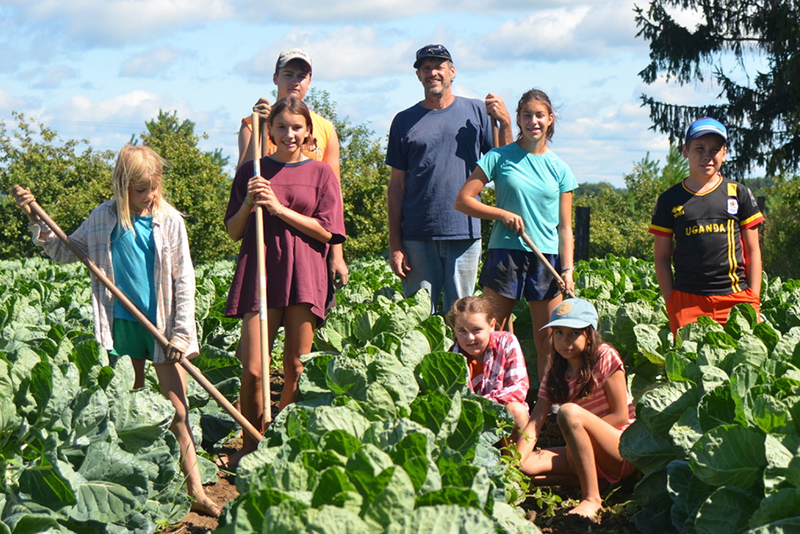 Jason Thimmesch, his kids, and some neighbors working in a vegetable patch on the farm