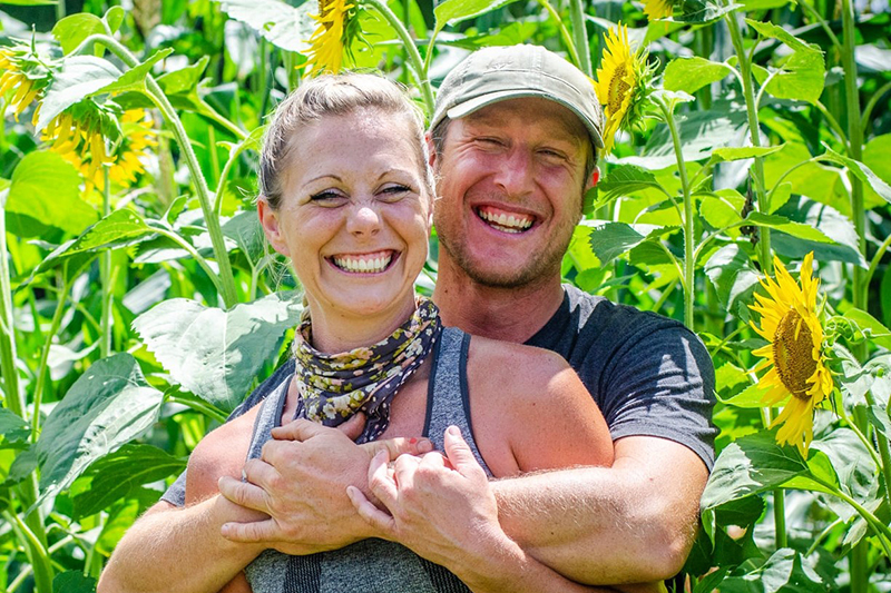 Joy Miller and Rufus Hauke of Keewaydin Farms embracing in a sunflower field