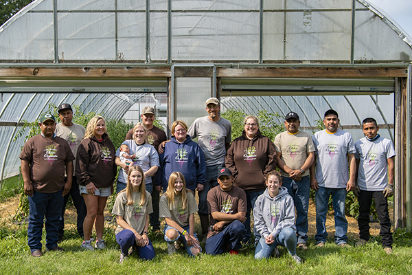 Olden Organics crew posing in front of a greenhouse