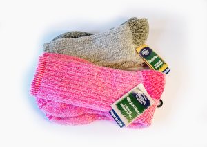 two folded hand knit socks. One pair is grey, one pair is bright pink