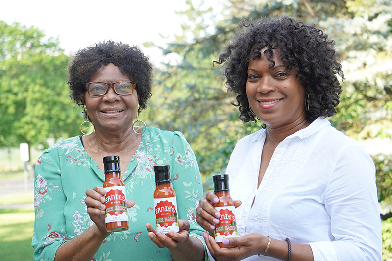 Two women holding bottles of hot sauce