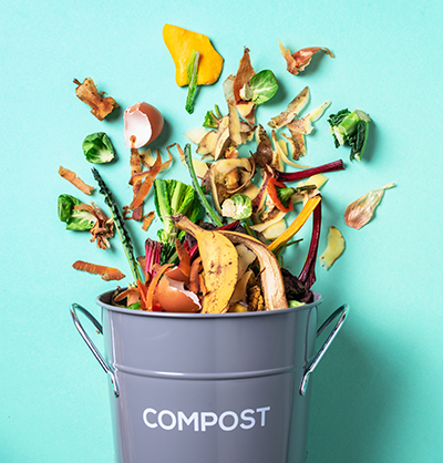 Trash bin for composting with kitchen scraps bursting out of it 