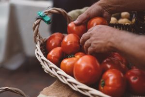 A person holding a basket full of tomatoes