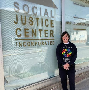 Kristin Mathews standing in front of the Social Justice Center's front window