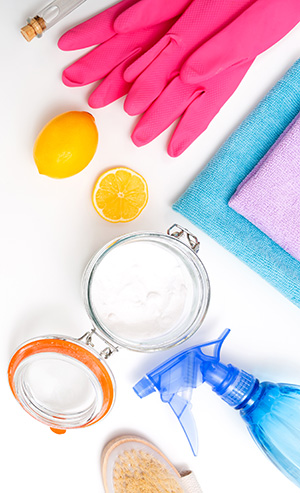 Rubber kitchen gloves, a lemon, towels, a canister of baking soda, and a spray bottle