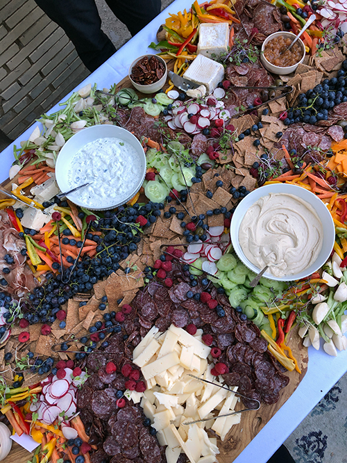 A huge platter filled with meats, cheeses, dips, and vegetables