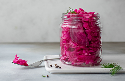 fermented cabbage with beets in a jar. horizontal image, gray background, copy space