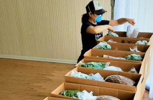 A person packing boxes with fresh produce for distribution