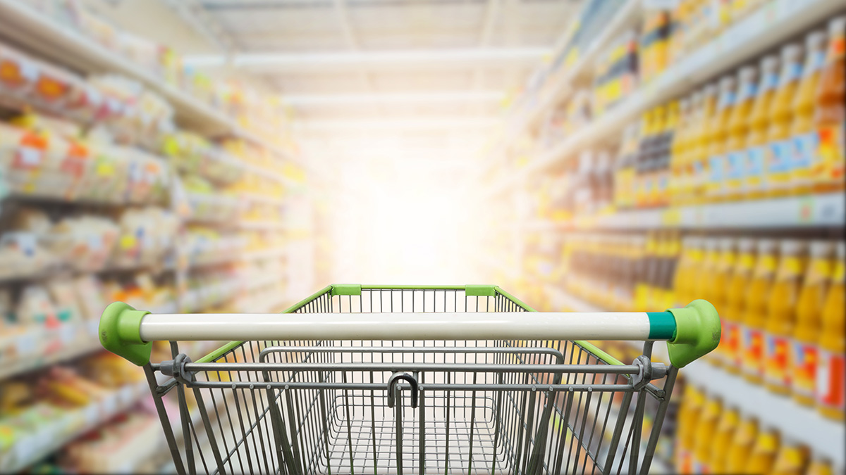 Supermarket aisle with empty green shopping cart