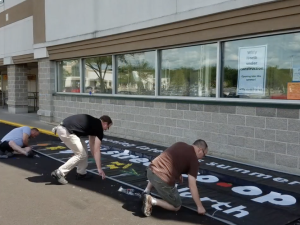 Three men prepping a sign to be hung outside Willy Street Co-op North