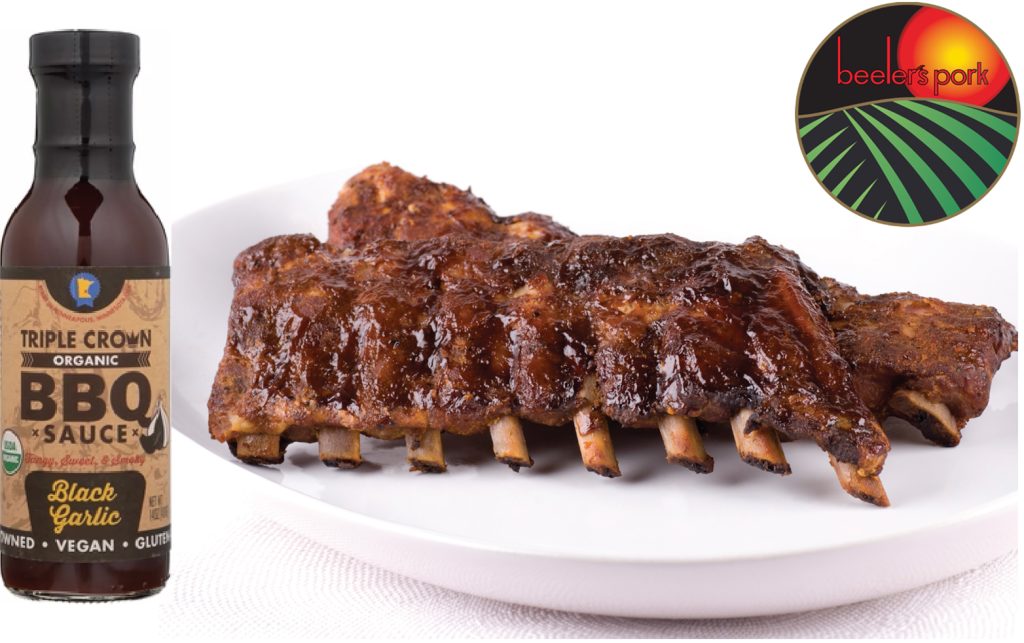 A plate of Beeler's Baby Back Ribs next to a jar of Triple Crown Black Garlic BBQ Sauce