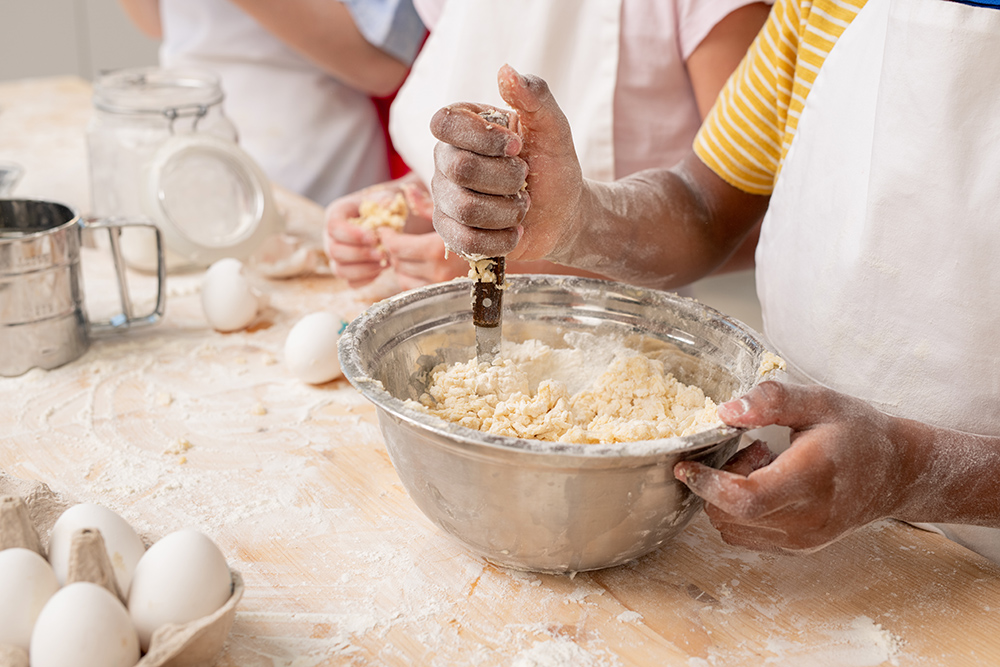 Kids gathered together at spacious kitchen and making delicious surprise for mom